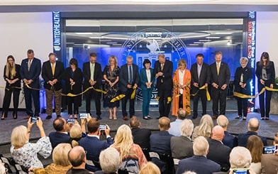 Picture of a row of People Cutting the Ribbon during the Ribbon Cutting Ceremony in front of the ORU's Capital Markets Trading Floor.